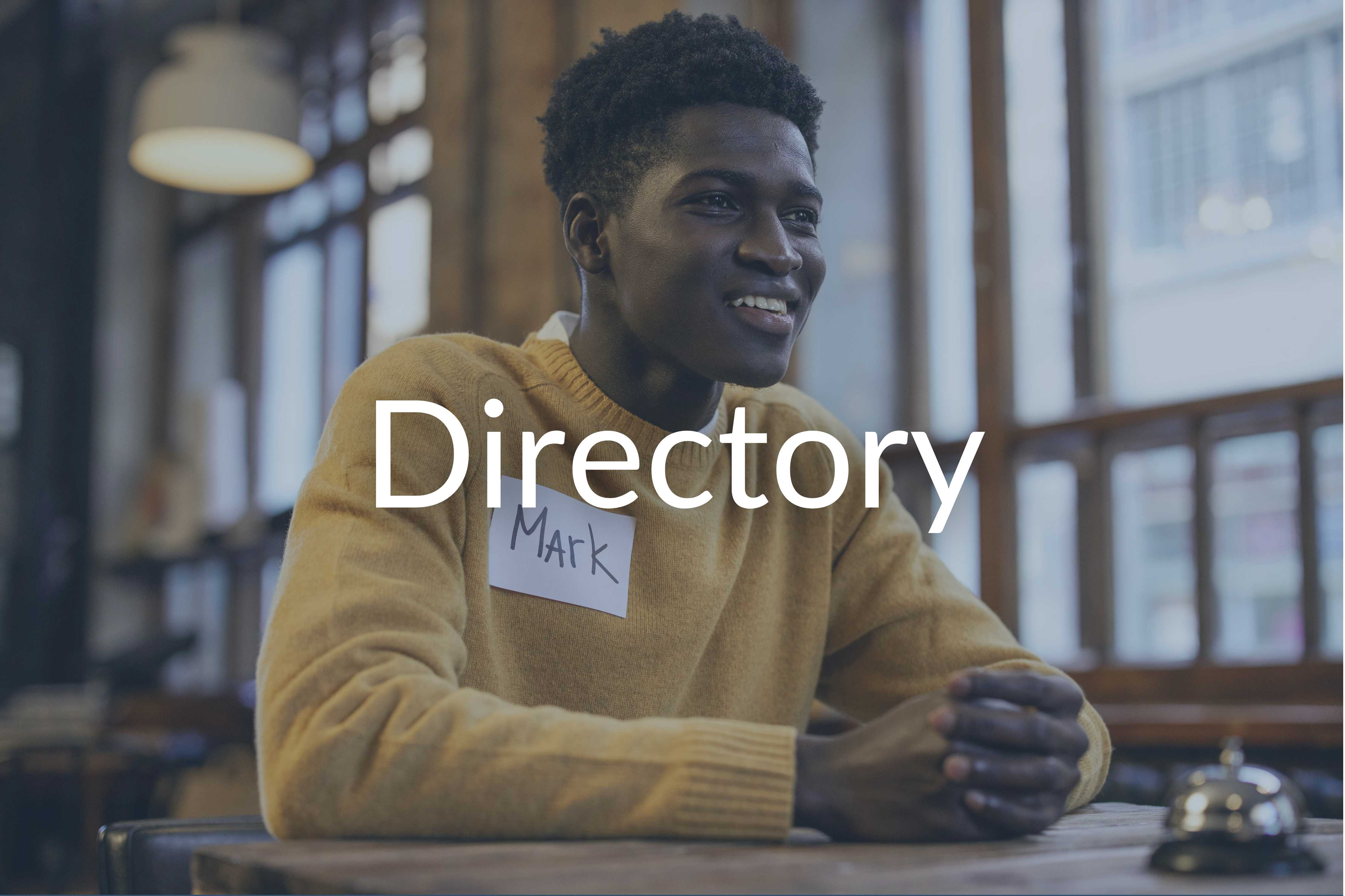 Young man sitting at desk with bell on it. Includes the word Directory.